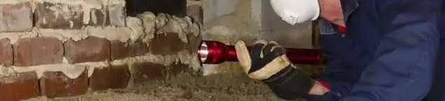 Pest control technician inspecting a crawl space for ant activity and entry points in Des Moines, IA