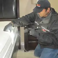 Bed bug inspection technician checking a mattress and bed frame for signs of infestation in Des Moines, IA