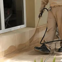 General pest control technician spraying exterior perimeter around a home in Des Moines, IA