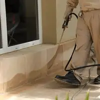 General pest control technician spraying exterior perimeter around a home in Des Moines, IA