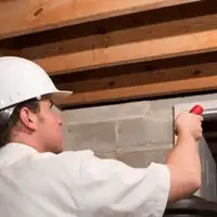 Termite inspection technician checking a basement wall and framing for termite activity in Des Moines, IA